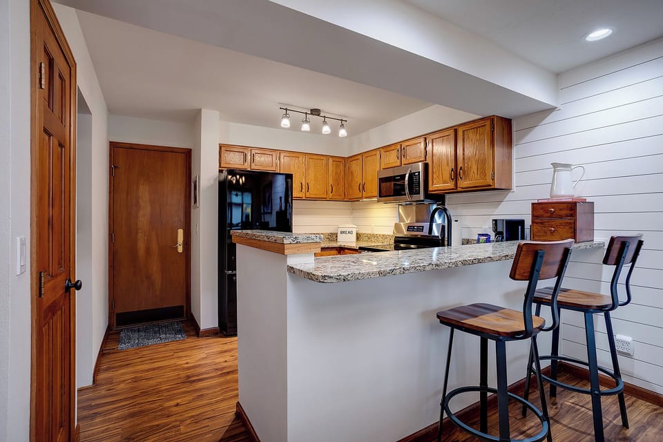 Your fully equipped kitchen features granite countertops, warm wood cabinets, and a breakfast bar perfect for morning coffee or casual meals.