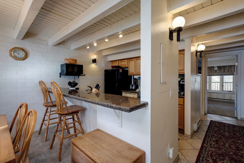 Gather around your charming breakfast bar with granite counters and rustic beamed ceilings creating the perfect cozy morning spot.