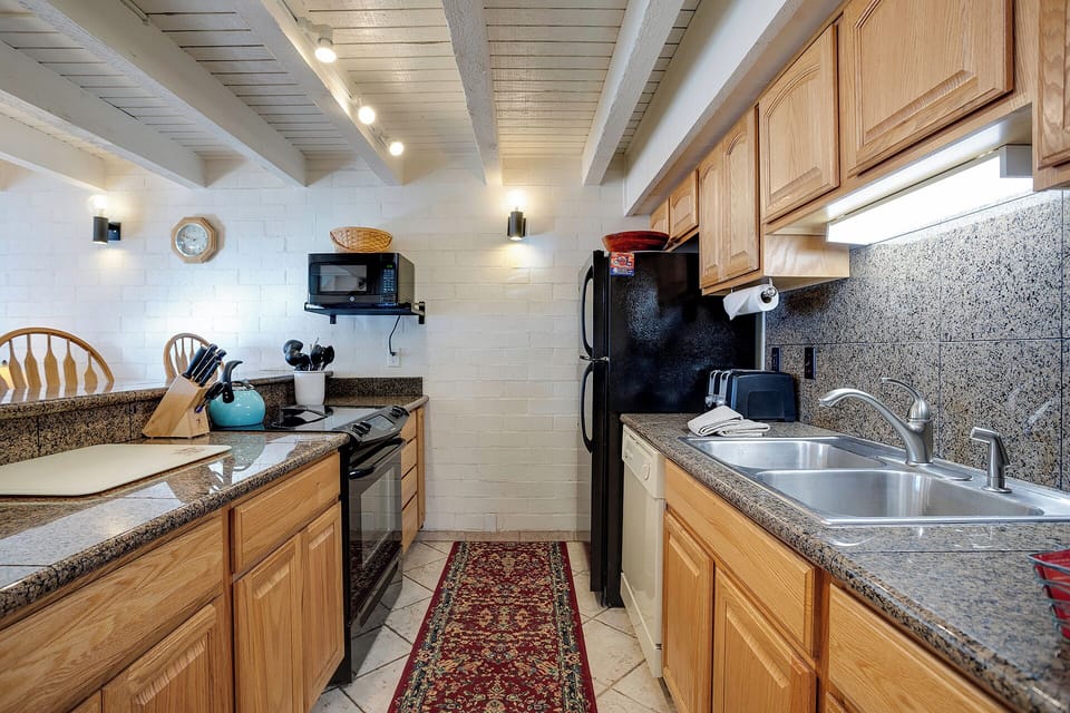 Your fully equipped kitchen features granite countertops, warm wood cabinets, and modern appliances for creating memorable meals.