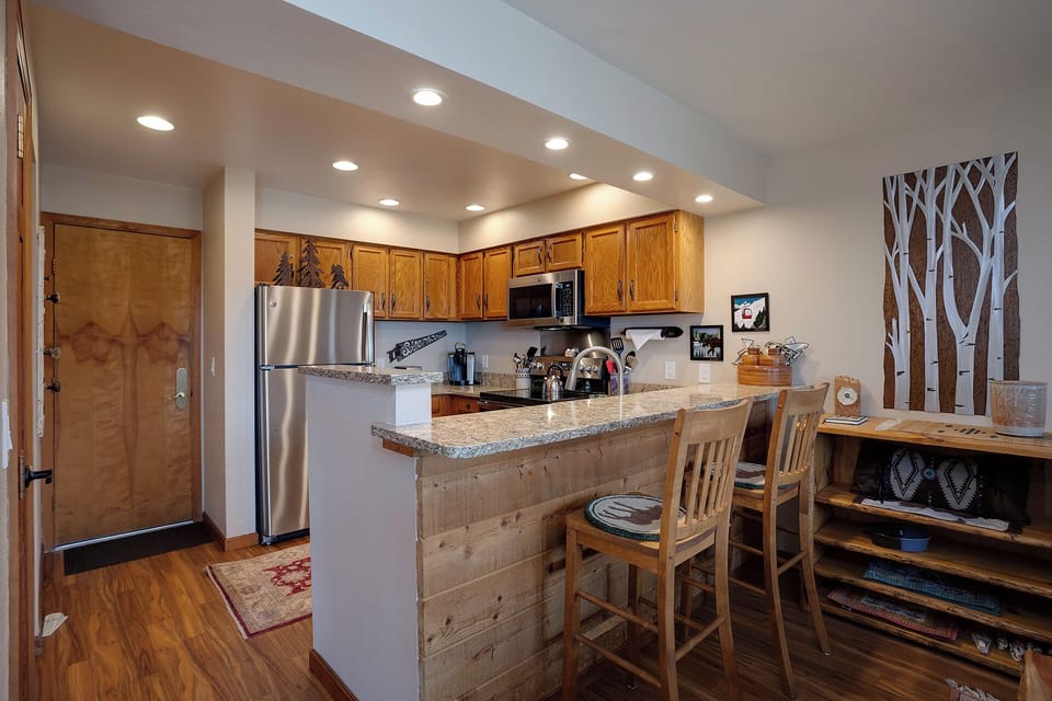 Your fully-equipped kitchen features warm wood cabinetry, granite countertops, and a breakfast bar perfect for morning coffee or casual dining.