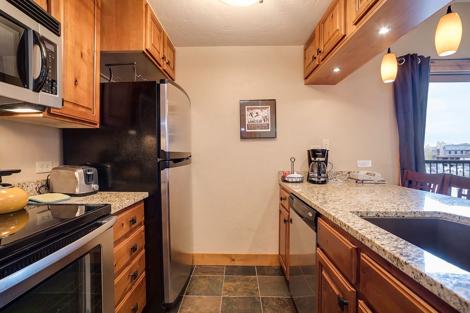 Your fully equipped kitchen features warm wood cabinets, granite countertops, and modern appliances—perfect for preparing meals during your stay.