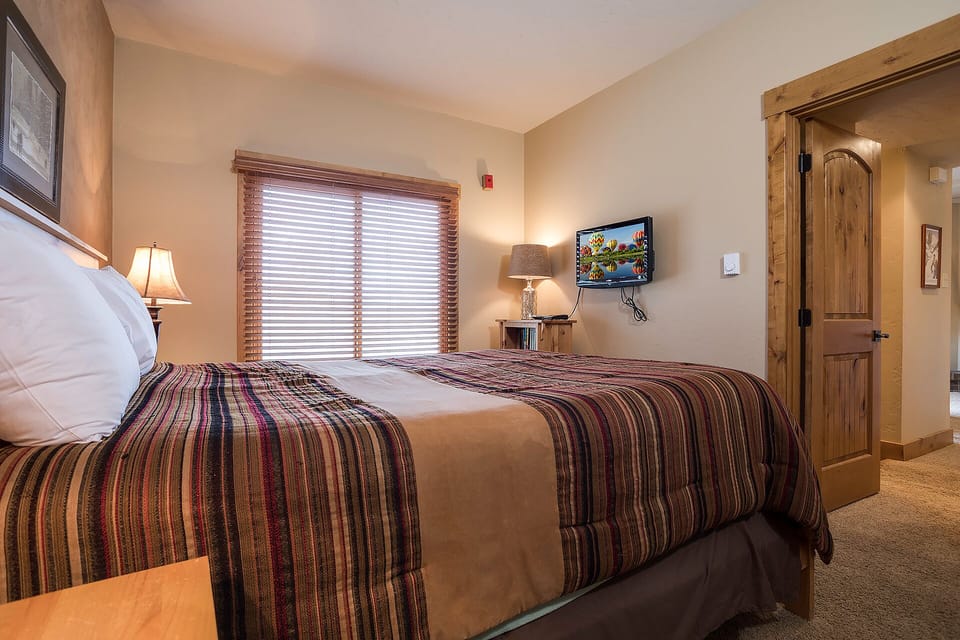 Sink into crisp linens and colorful blankets in your cozy bedroom, complete with flatscreen TV and warm lighting for perfect relaxation.