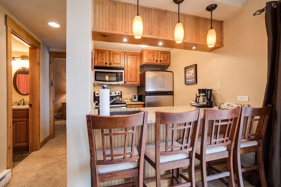 Your fully-equipped kitchen awaits with granite counters, pendant lighting, and comfortable bar seating for memorable meals together.