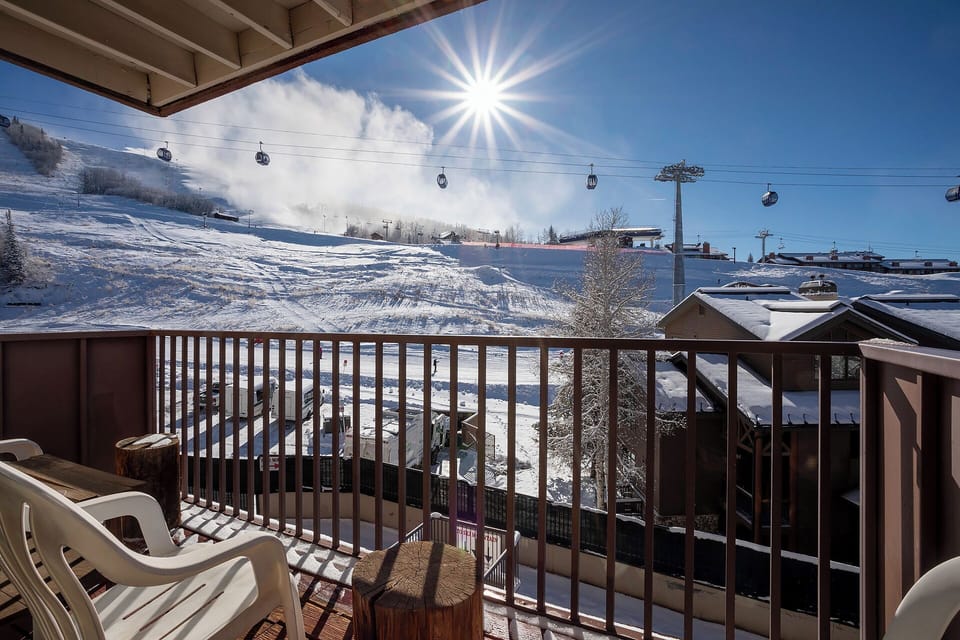 Ski resort balcony with gondola lifts and snowy mountain slopes under bright winter sun.