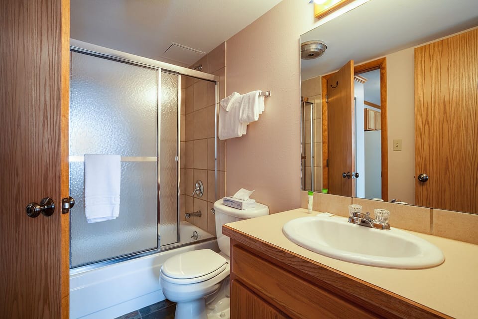 Step into a welcoming bathroom with a spacious shower-tub combo, soft towels within reach, and a well-lit vanity—your personal retreat where you can unwind after a day exploring the area.