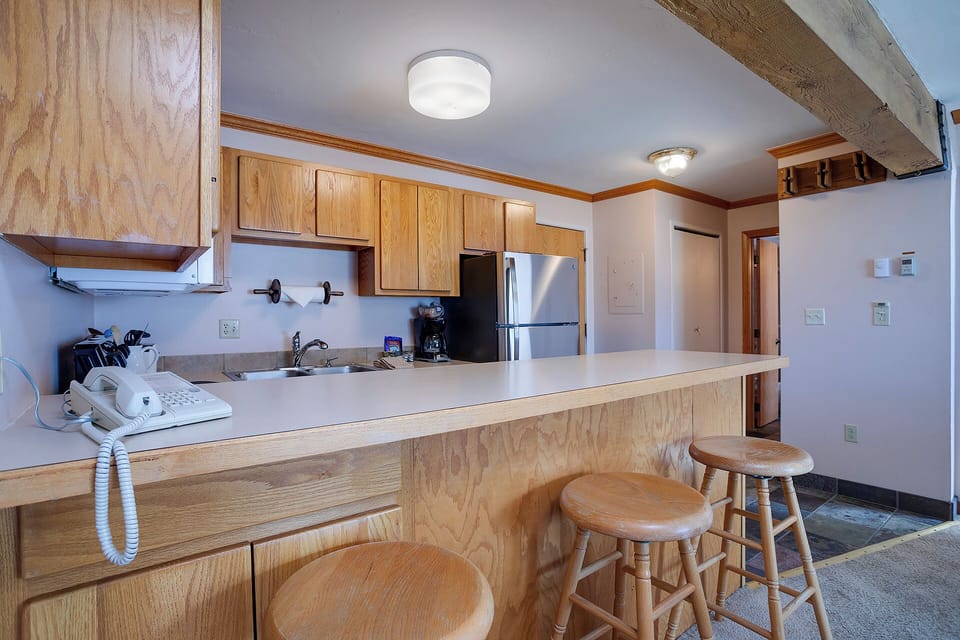 Your fully equipped kitchen welcomes with warm wood cabinetry and a breakfast bar perfect for morning coffee or casual meals.