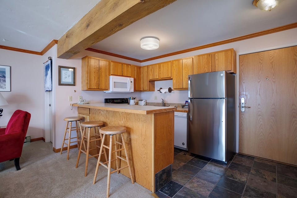 Your fully-equipped kitchen awaits with warm wood cabinetry, modern appliances, and a convenient breakfast bar for morning coffee or casual meals.