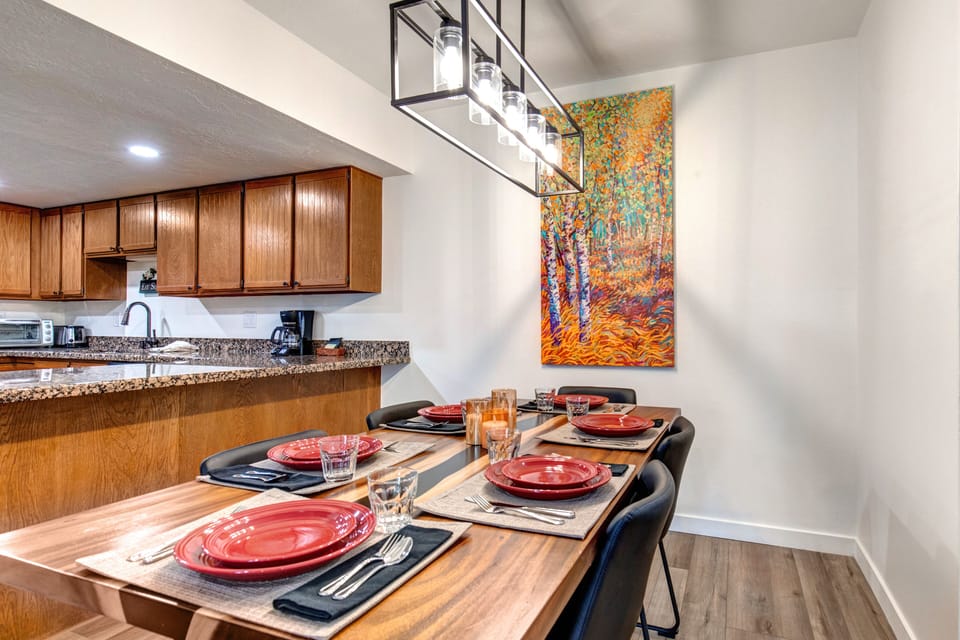 Park Station 133 has a dining table set for 6 guests, with a colorful paintings of aspens hanging on the wall.
