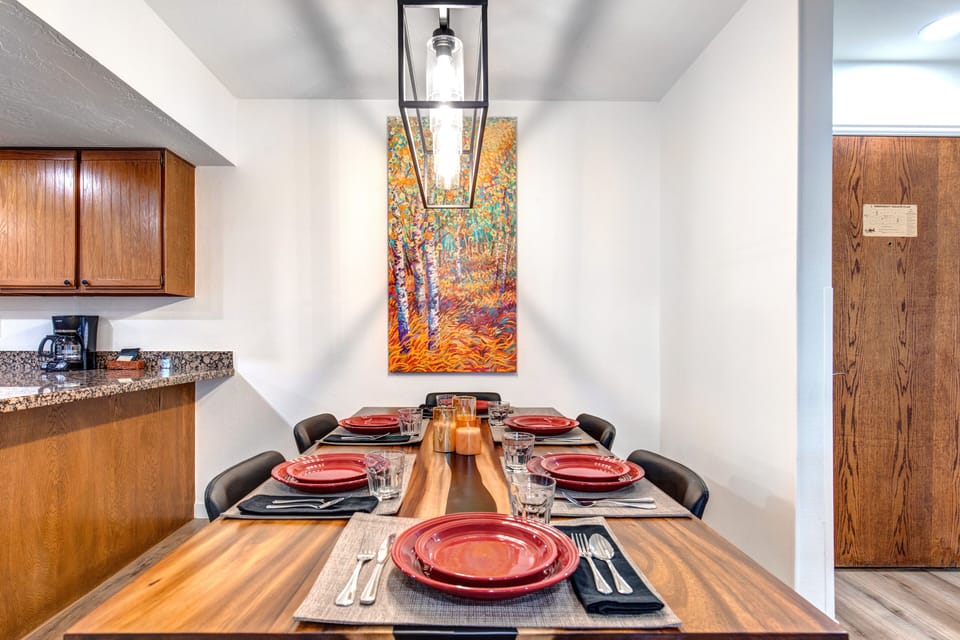 Park Station 133 has a dining table set for 6 guests, with a colorful paintings of aspens hanging on the wall.