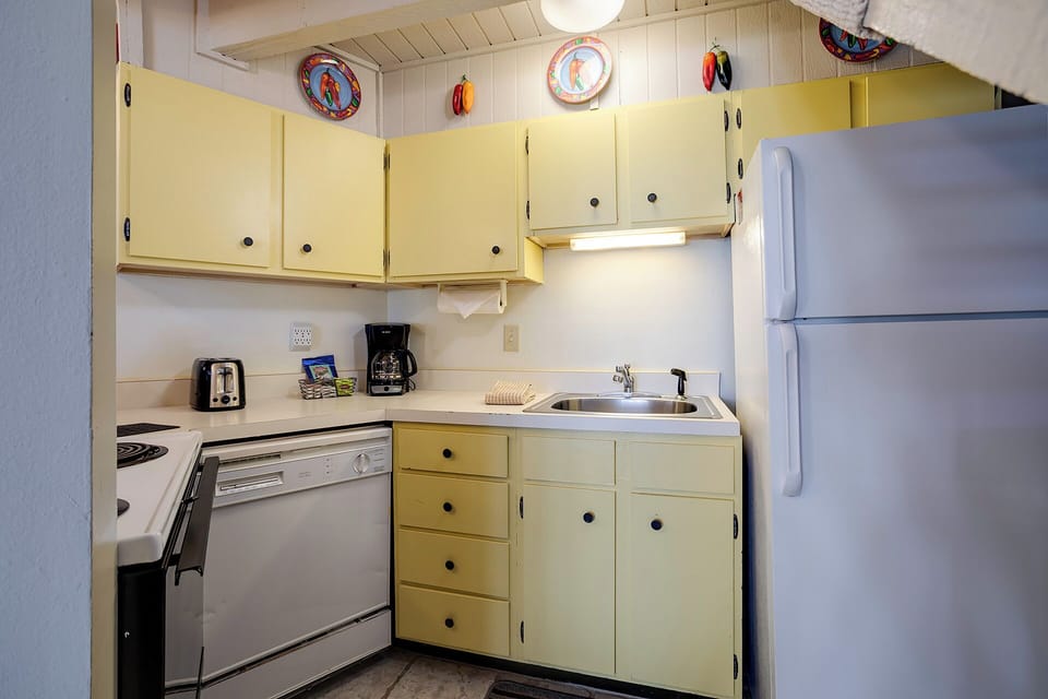 Your fully equipped kitchen makes meal prep a breeze with modern appliances and charming yellow cabinets.