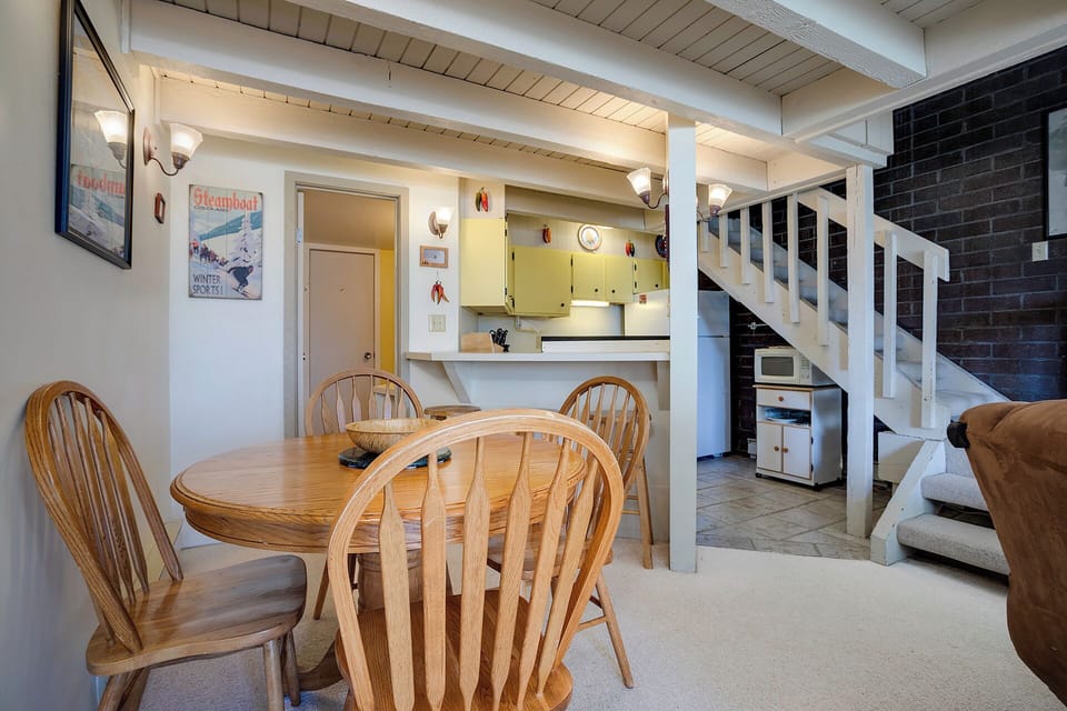 Cozy open-concept space where you can cook, dine, and relax with rustic wood beams and charming ski-themed decor creating a warm alpine atmosphere.