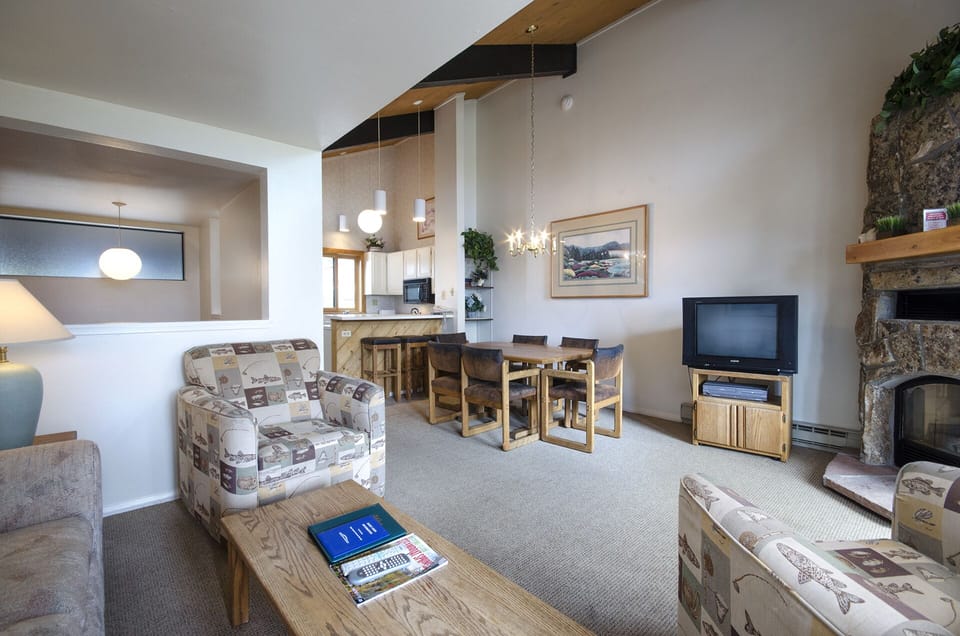 Relax in your spacious living room with cozy seating, stone fireplace, and open kitchen—perfect for memorable evenings together.
