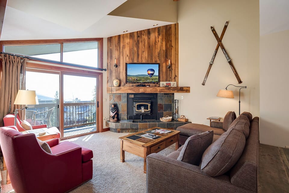 Unwind in your cozy living room where rustic charm meets comfort—crackling fireplace, mountain views, and plush seating create the perfect retreat.