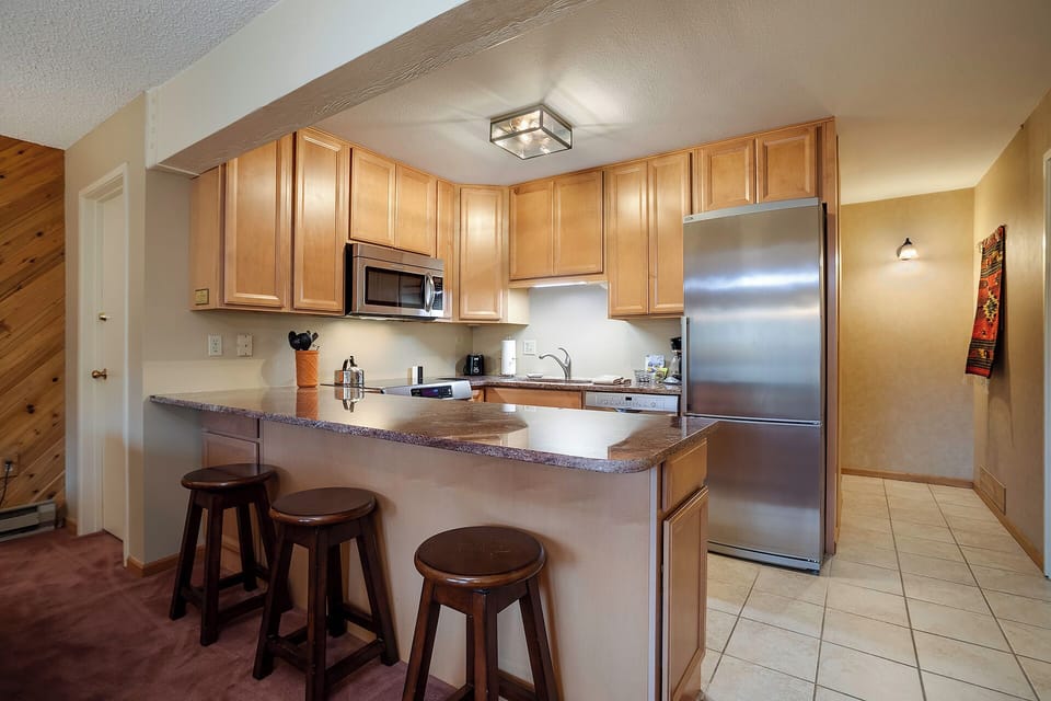 Your fully equipped kitchen features granite counters, stainless appliances, and a breakfast bar perfect for morning coffee or casual meals together.