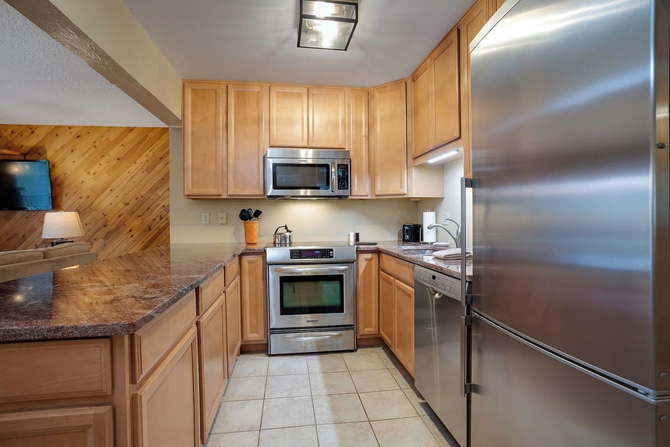 Your fully equipped kitchen features granite counters, stainless appliances, and warm wood cabinets—perfect for preparing meals during your stay.