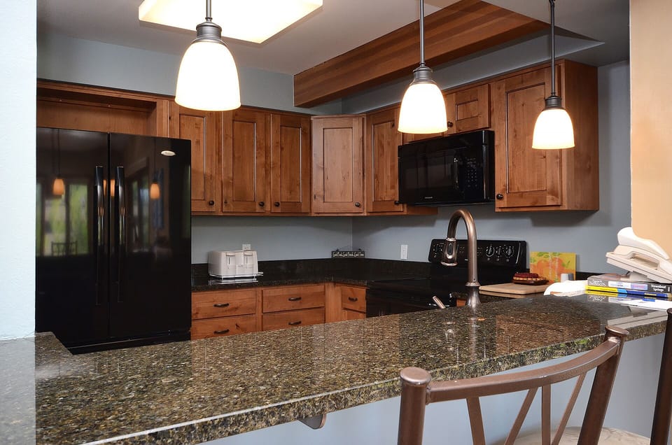 Your fully-equipped kitchen features warm wood cabinetry, granite countertops, and modern appliances perfect for preparing memorable meals during your stay.