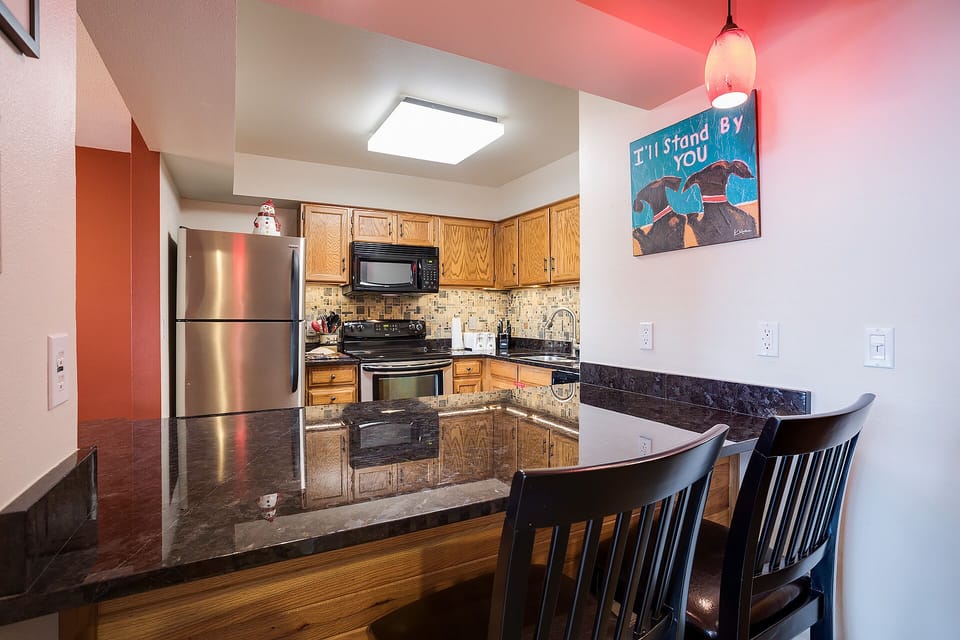 Your fully equipped kitchen awaits with granite counters, stainless appliances, and a breakfast bar perfect for morning coffee or casual meals.