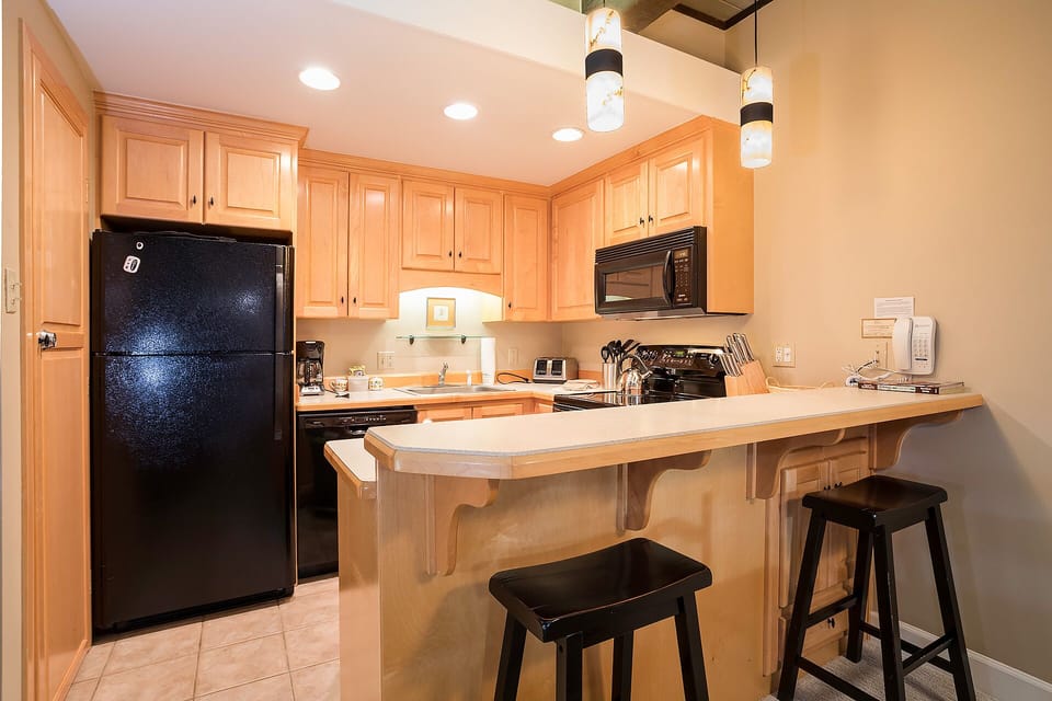 Your fully equipped kitchen features warm wood cabinets, modern appliances, and a breakfast bar perfect for morning coffee.
