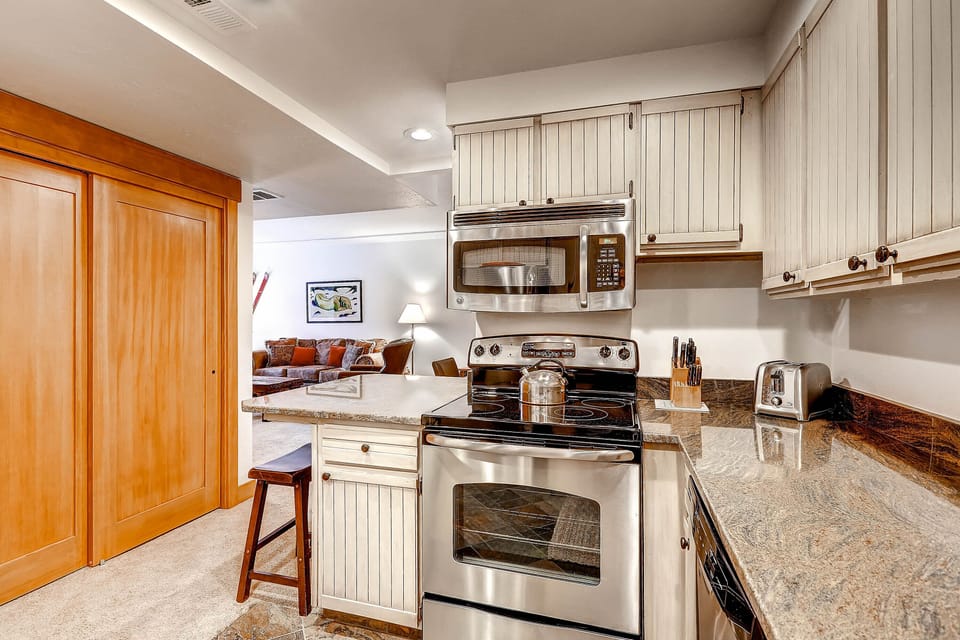 Park Station 134's kitchen with breakfast bar with seating for two, granite counters, and stainless steel microwave and oven.34-Kitchen