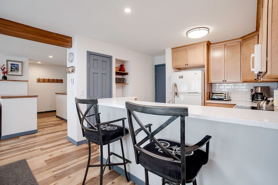Your modern kitchen features warm wood cabinetry, white countertops, and a breakfast bar where you can enjoy morning coffee together.