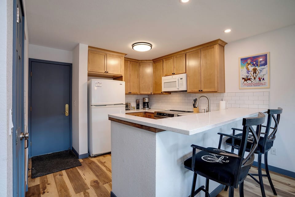 Your fully equipped kitchen features warm wood cabinets, modern appliances, and a breakfast bar perfect for morning coffee or casual meals.