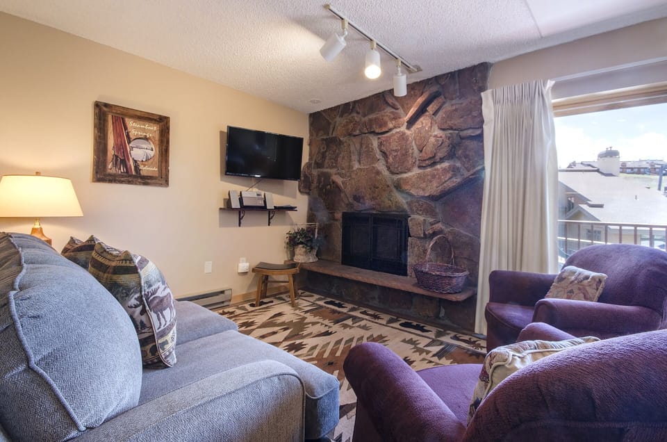 Cozy up by your stone fireplace while winter views frame this perfect mountain retreat living room.