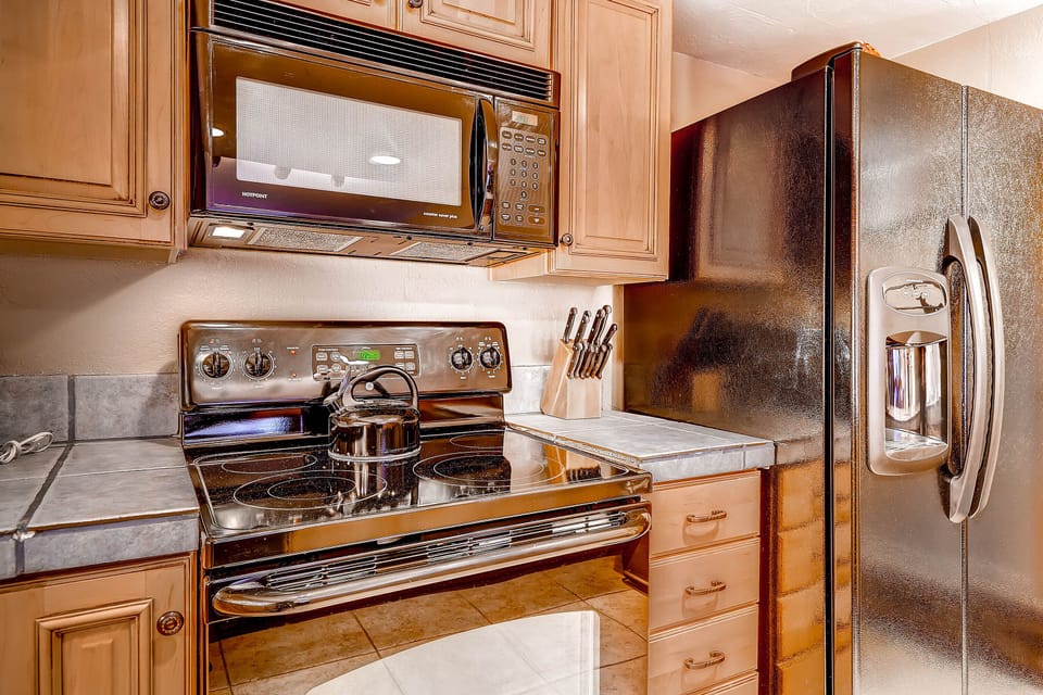 The well equipped kitchen with wood cabinets and black appliances.
