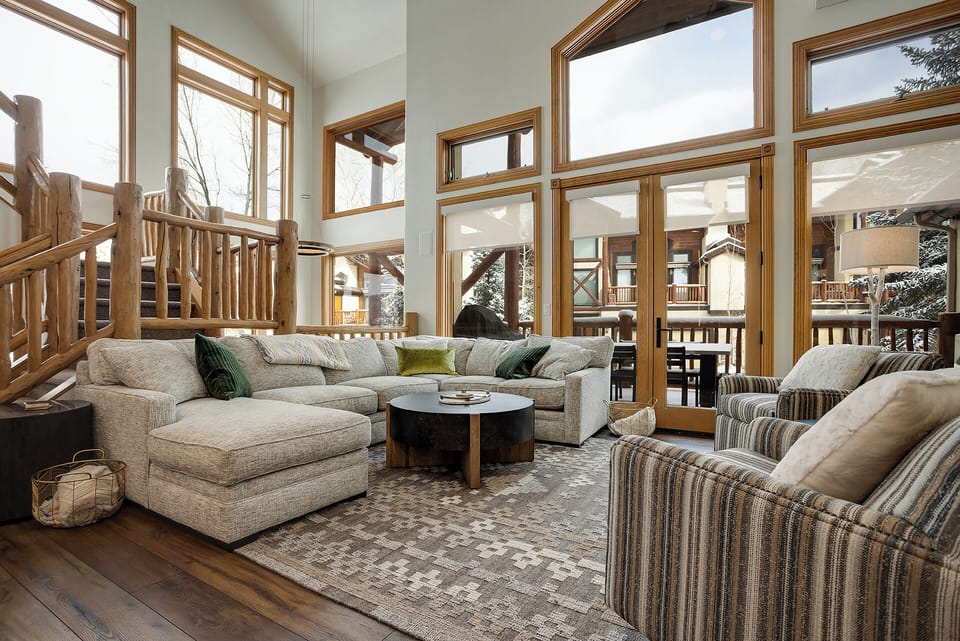 Sink into plush sofas in this stunning mountain retreat, where soaring windows frame snowy forest views and rustic log accents create your perfect alpine escape.