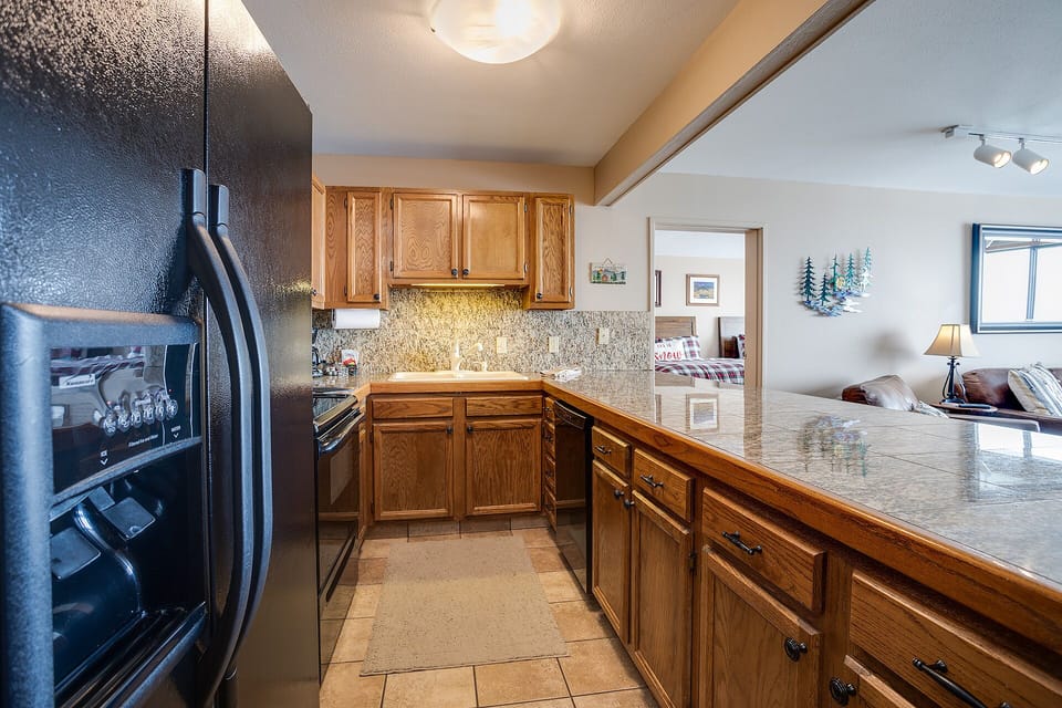 Your fully equipped kitchen awaits with granite counters, warm wood cabinets, and modern appliances for memorable home-cooked meals during your stay.