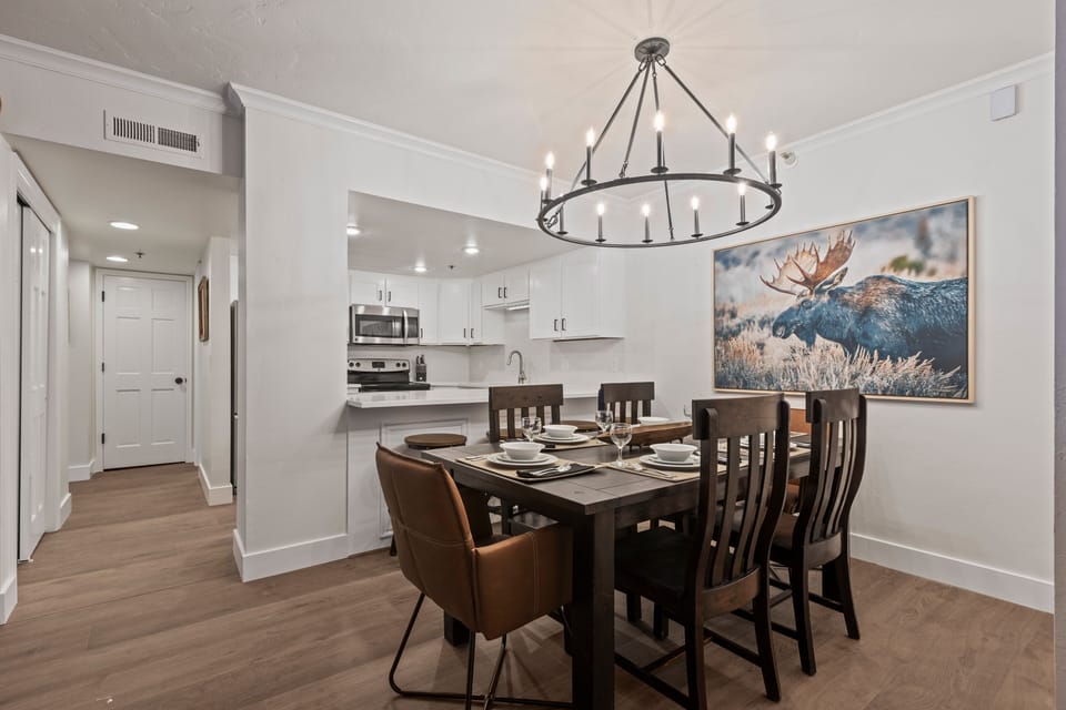 The dining table has 6 chairs, beautiful chandelier and moose artwork.