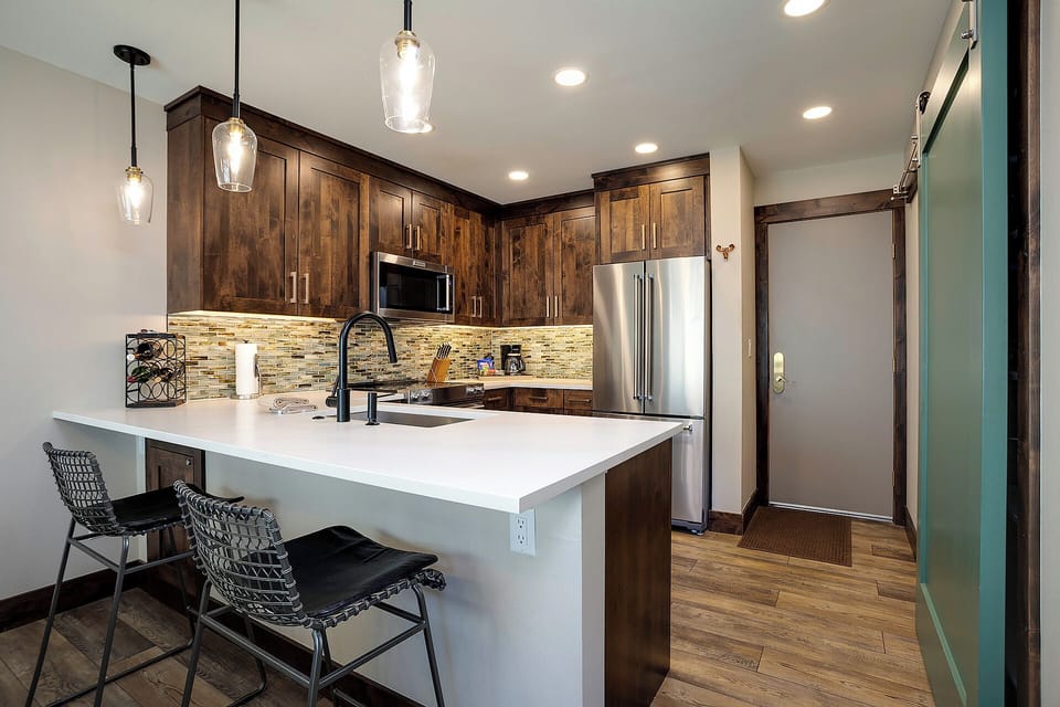 Your modern kitchen features rich wood cabinetry, sleek pendant lighting, and a spacious island perfect for morning coffee or cooking together.