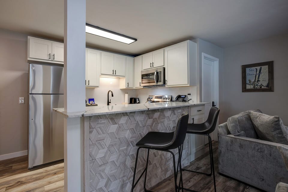 Your stylish kitchen features gleaming stainless appliances, crisp white cabinetry, and a stunning tiled breakfast bar perfect for morning coffee.