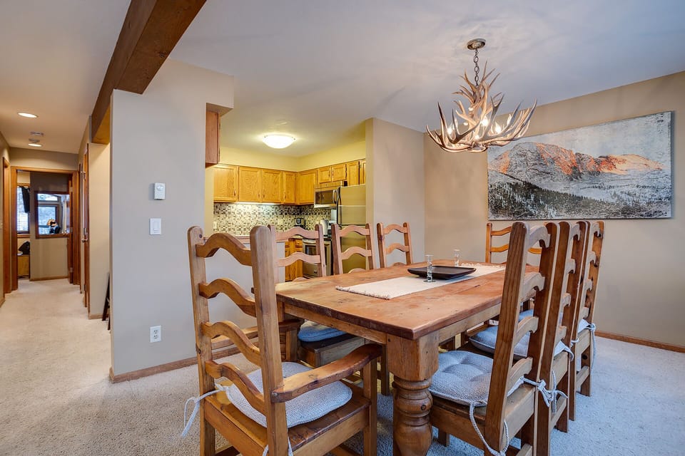 Gather around your rustic dining table under the stunning antler chandelier, where mountain views and warm wood create the perfect alpine dining experience.