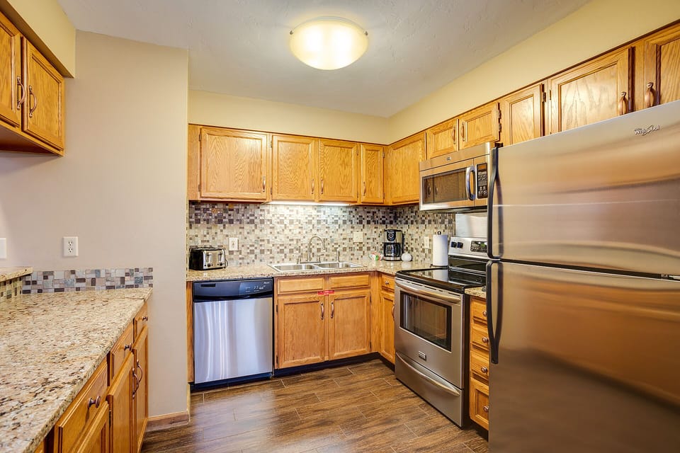Your fully-equipped kitchen features stainless steel appliances, granite countertops, and beautiful mosaic backsplash - perfect for preparing meals during your stay.