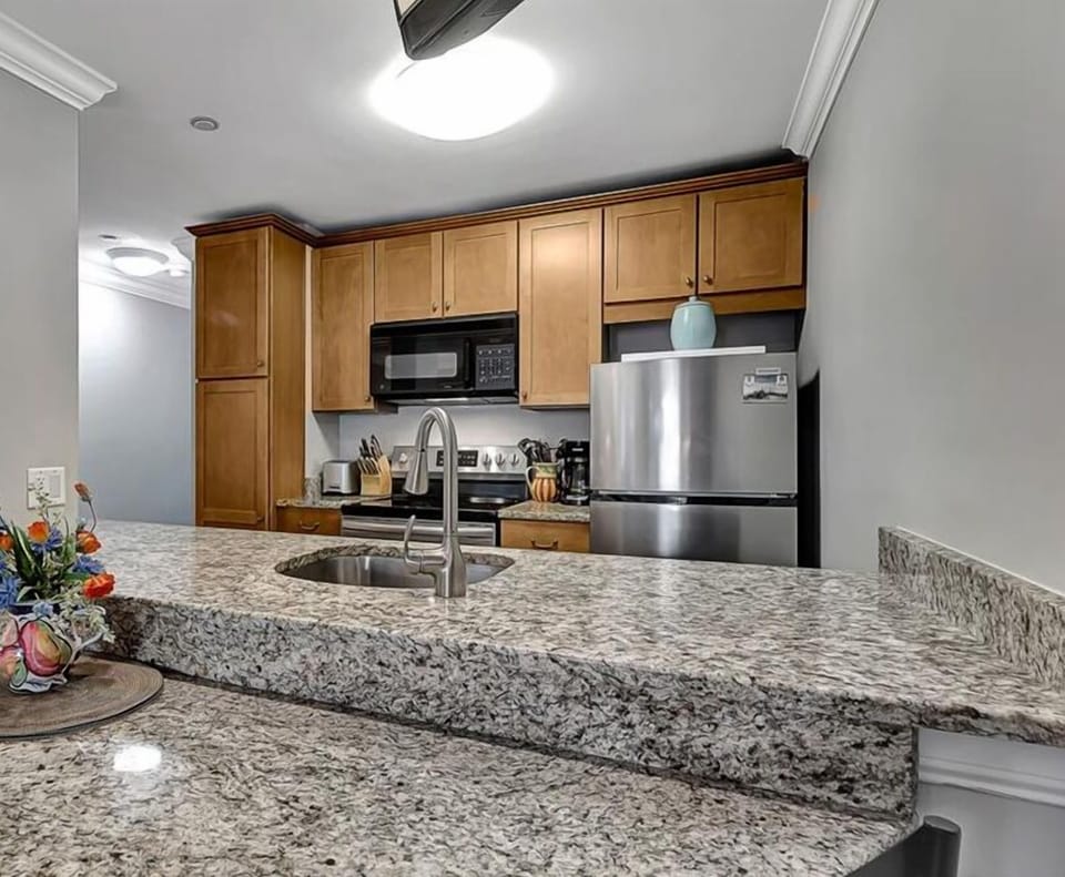 Ocean Dunes 102 - Kitchen - Beautiful granite countertops and attached dining table looks into a fully equipped kitchen.