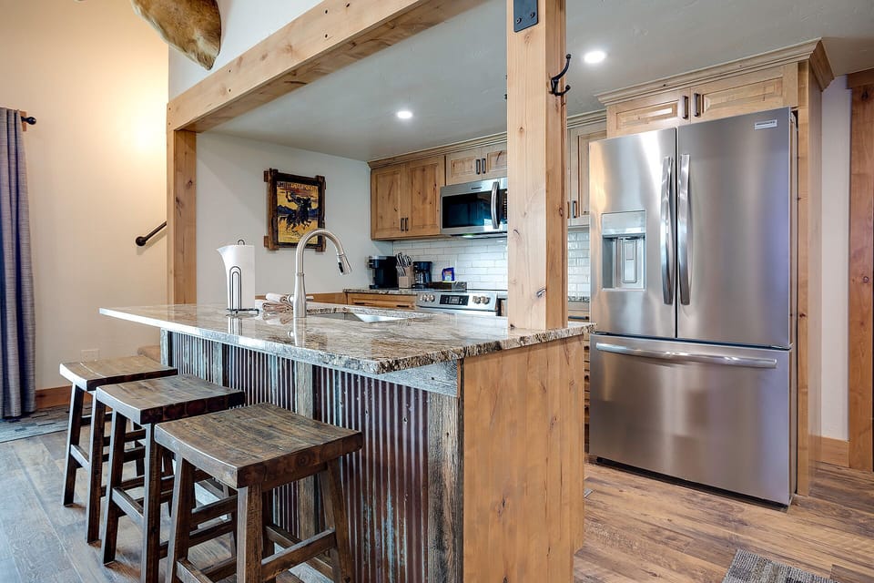 Step into your mountain retreat kitchen where granite counters and rustic wood beams create the perfect space for morning coffee and cozy meals together.