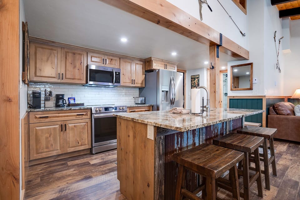 Your rustic kitchen features warm wood cabinets, granite countertops, and exposed beams creating a cozy mountain retreat atmosphere.