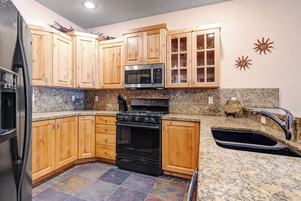 Your fully equipped kitchen features granite countertops, modern appliances, and warm wood cabinetry—perfect for preparing homemade meals during your mountain getaway.