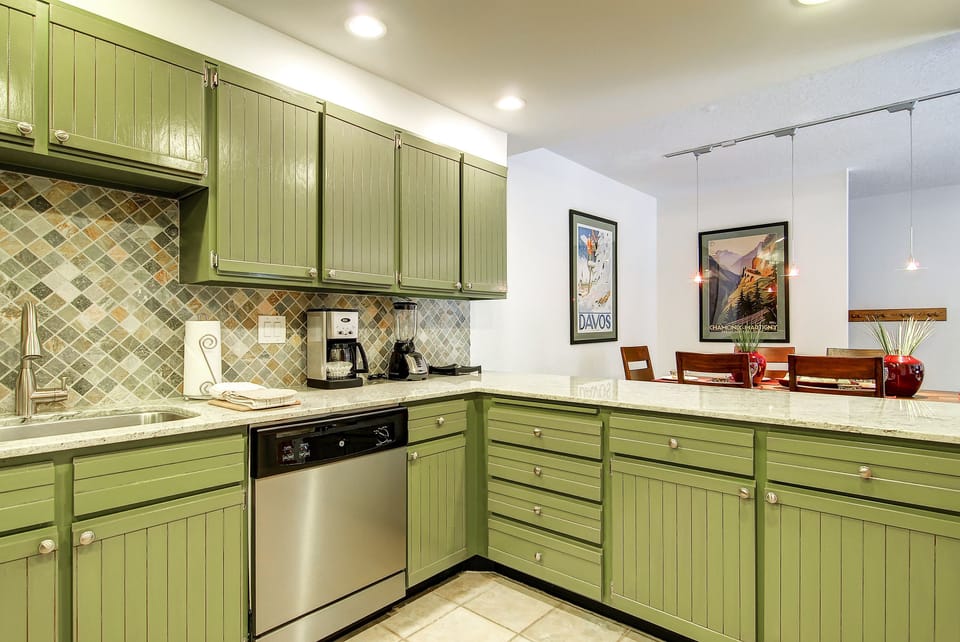 The well equipped kitchen with stainless steel appliances and green cabinets.