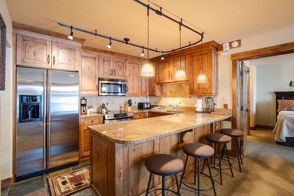Your fully equipped kitchen features warm wood cabinetry, granite countertops, and modern appliances for preparing memorable meals together.