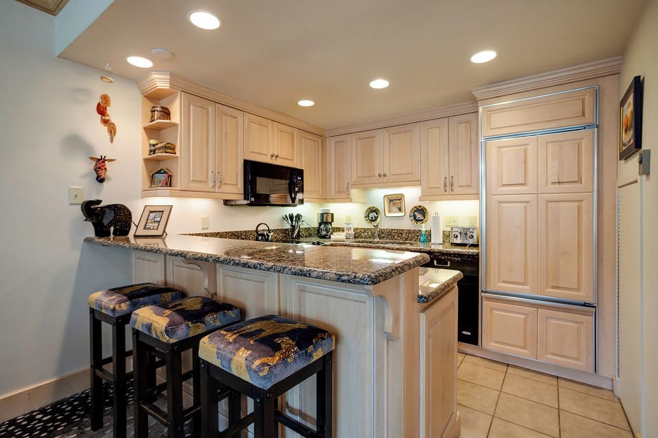 Your fully equipped kitchen features granite countertops, stainless steel appliances, and a convenient breakfast bar with stylish seating for casual dining.