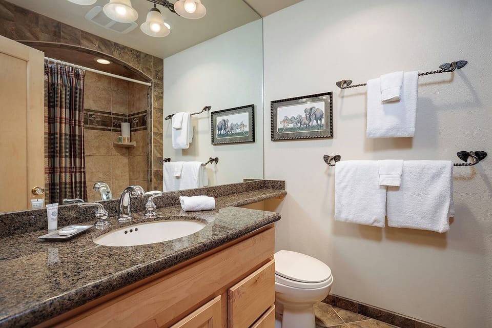 Step into your private bathroom, where rich granite countertops, warm wood cabinetry, and plush towels await. The tiled shower and thoughtful touches create a welcoming retreat after your day of adventure.