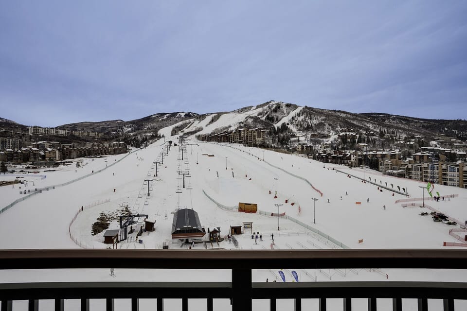 Panoramic ski resort view from balcony showcasing pristine slopes, chairlifts, and mountain village below.