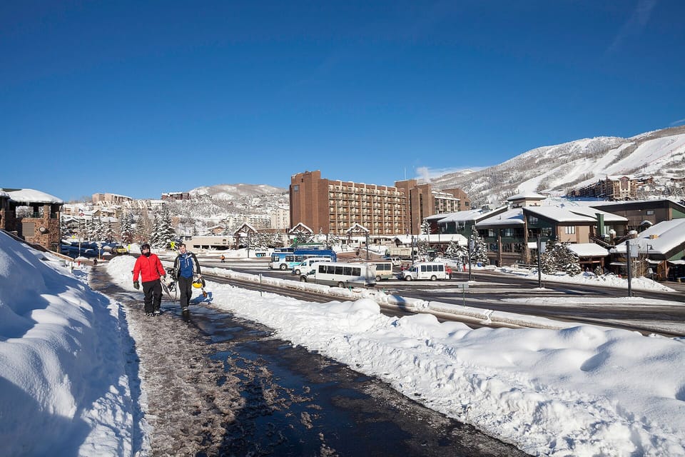 Winter resort village with snowy mountains, hotels, and convenient transit access for mountain adventures.
