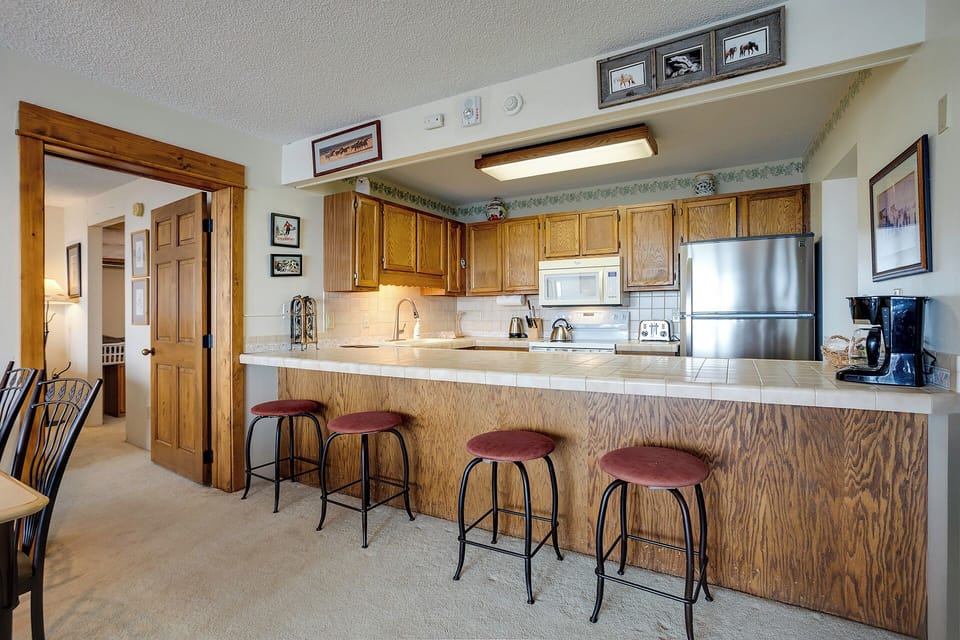 Your spacious kitchen awaits with warm wood cabinetry, stainless steel appliances, and a breakfast bar perfect for morning coffee or casual meals.