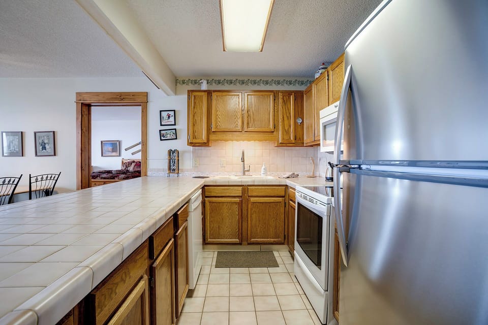 Your spacious kitchen features warm wood cabinets, tile countertops, and stainless steel appliances for all your culinary adventures.