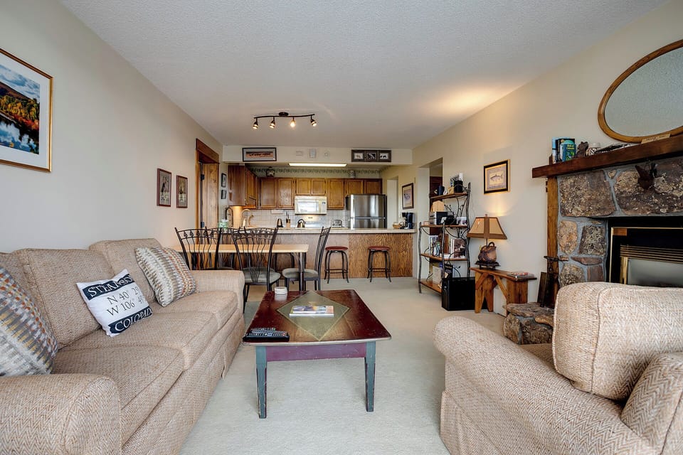 Relax in your cozy living space with plush seating, stone fireplace, and fully equipped kitchen—perfect for unwinding after mountain adventures.