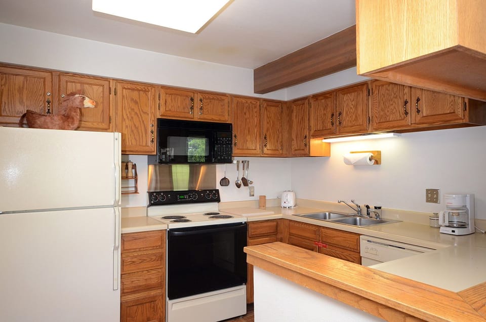 Your fully equipped kitchen features warm wood cabinets, modern appliances, and a charming skylight that fills the space with natural light.