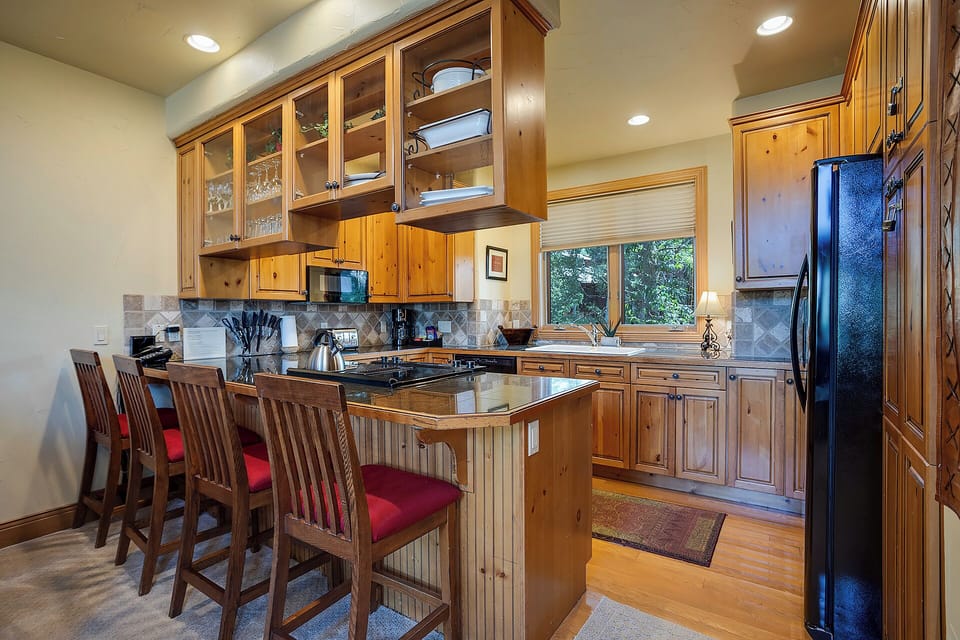 Your spacious kitchen features rich wood cabinetry, granite counters, and a breakfast bar perfect for morning coffee.