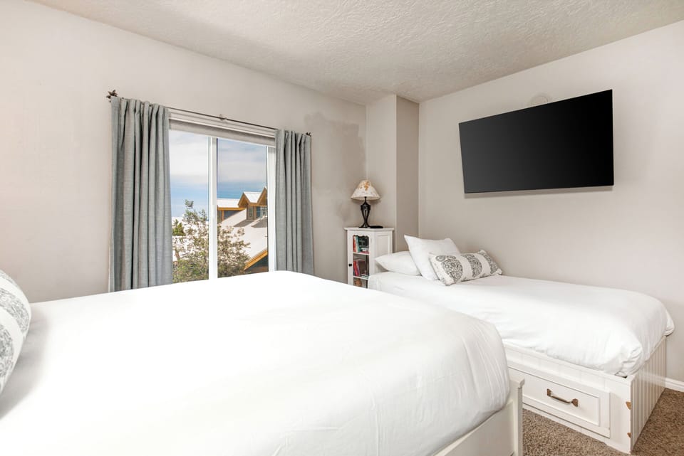 The second bedroom has a queen bed, twin bed, and white furniture.